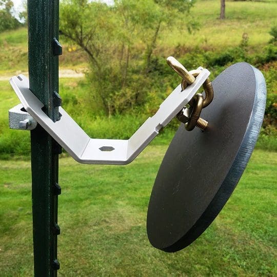 Close-up of a satellite dish mounted on a vertical green pole, showing the metal support arm and a circular dish plate secured with bolts.