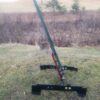 T Post stand 4 Hang Fast Targets Disassembled trailer jack and base resting on grass outdoors with a long green arm attached to a red mounting plate